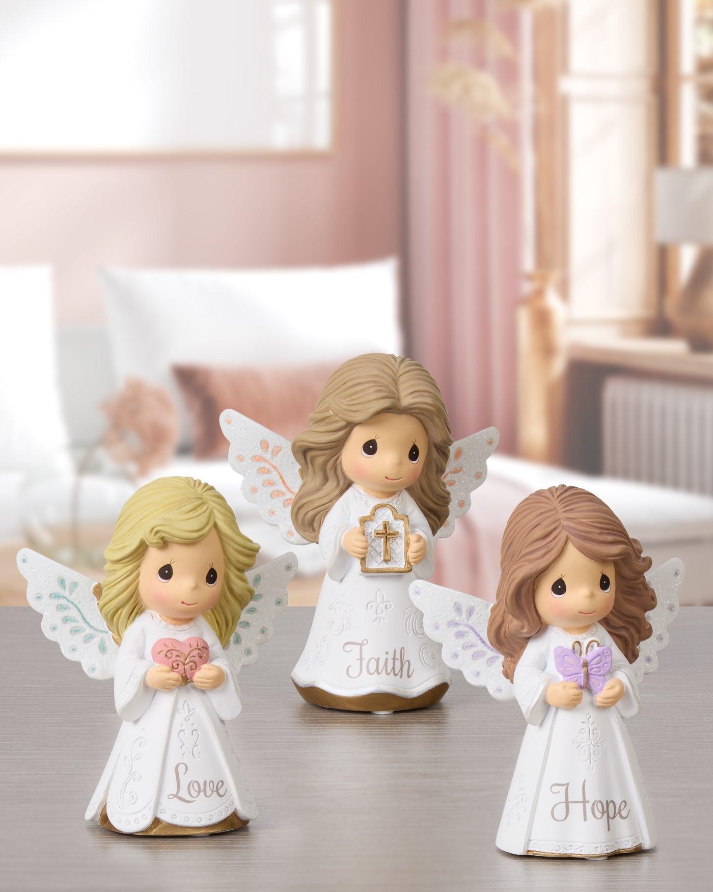 three mini angel figurines holding a heart, cross, and butterfly