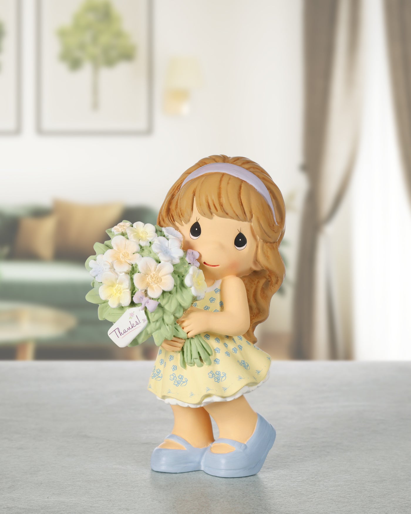 girl figurine in yellow dress holding bouquet of flowers and tag showing "thanks"